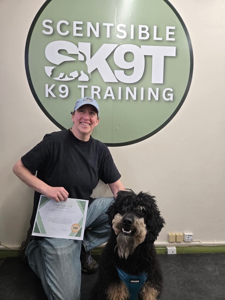 A group class graduate holding their certificate with their dog