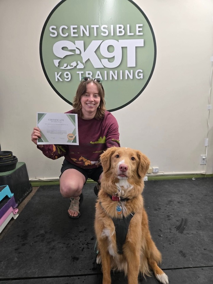 A client with their dog and class completion certificate